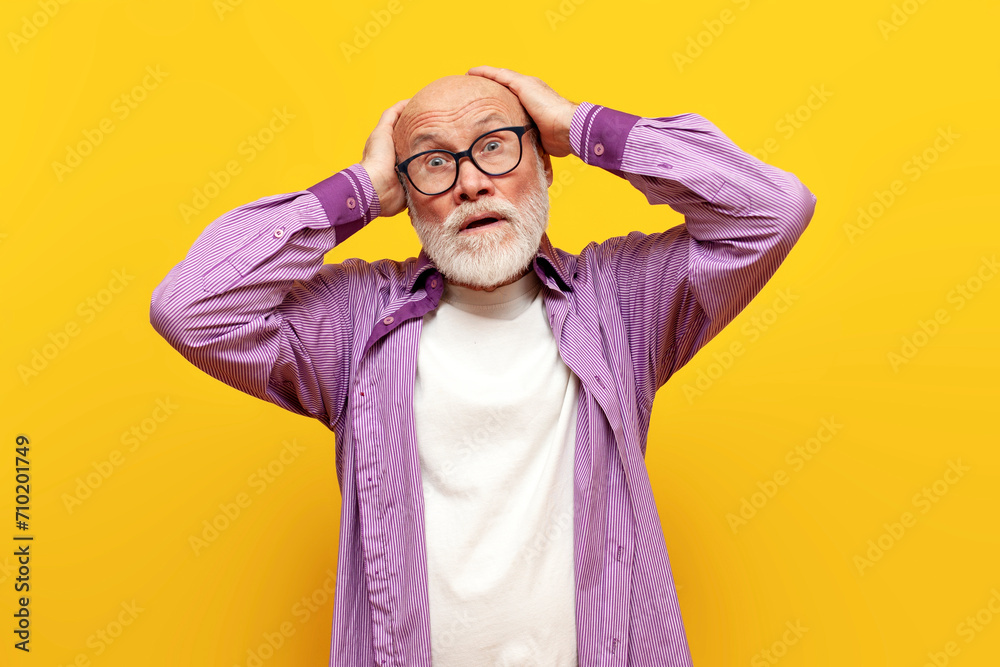 shocked old bald grandfather in glasses and purple shirt holds his head with his hands in amazement, elderly pensioner with gray beard looks excitedly at the camera and wonders shocked old bald grandfather in glasses and purple shirt holds his head with his hands in amazement, elderly pensioner with gray beard looks excitedly at the camera and wonders