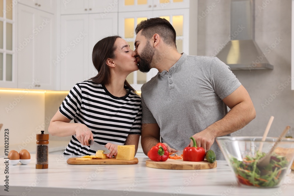 Lovely couple kissing while cooking in kitchen Lovely couple kissing while cooking in kitchen
