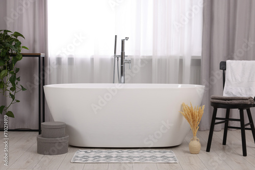 Stylish bathroom interior with soft bath mat and tub photo