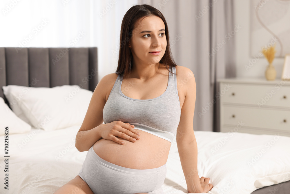 Beautiful pregnant woman in comfortable maternity underwear on bed at home Beautiful pregnant woman in comfortable maternity underwear on bed at home