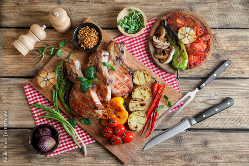 Delicious grilled meat and vegetables served on wooden table, flat lay