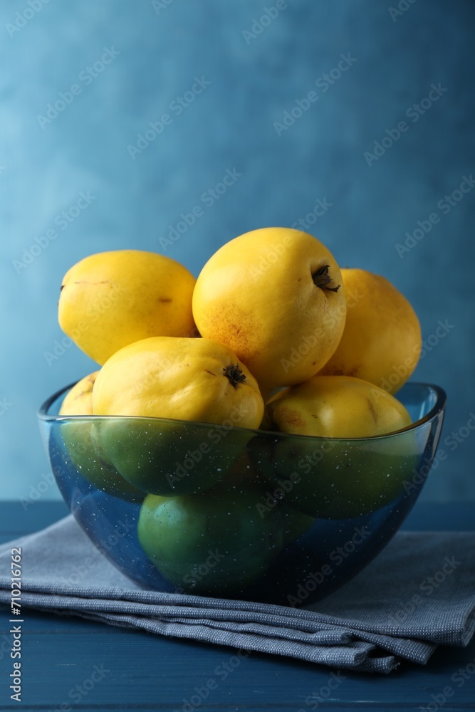 Tasty ripe quinces in bowl on blue wooden table Tasty ripe quinces in bowl on blue wooden table