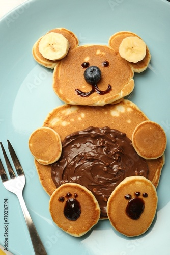 Creative serving for kids. Plate with cute bear made of pancakes, blueberries, bananas and chocolate paste, top view