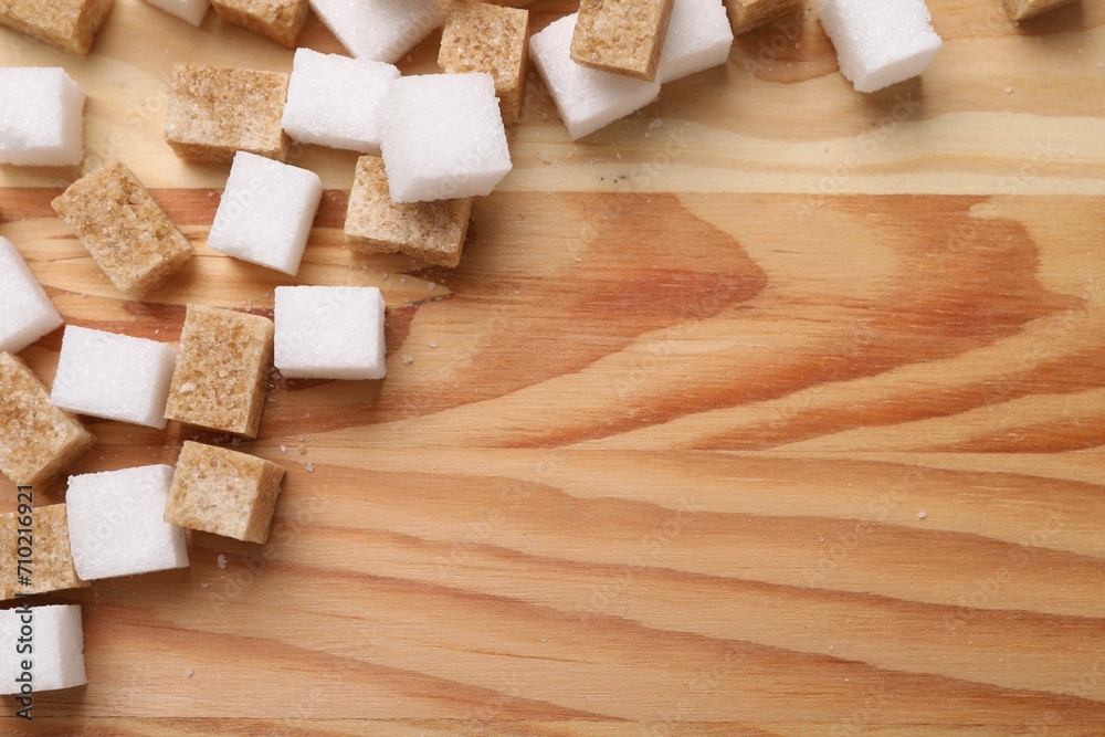 White and brown sugar cubes on wooden table, flat lay. Space for text