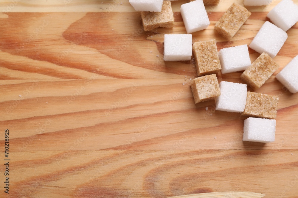 White and brown sugar cubes on wooden table, flat lay. Space for text