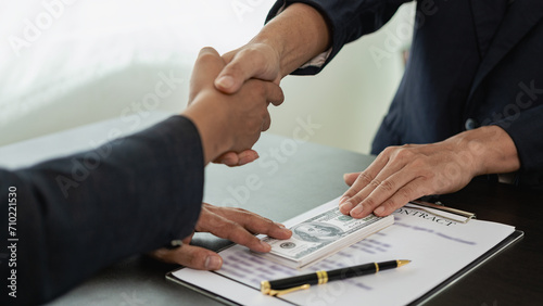 Government officials receive bribes from businessmen who have ideas about corruption and anti-bribery. Businessman's hand holding bribe to official signing contract for business project photo