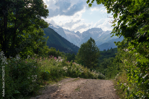 View of the Dombay-Ulgen gorge in the mountains of the North Caucasus and the trail to the Chuchkhur waterfall near the village of Dombay on a sunny summer day, Karachay-Cherkessia, Russia photo