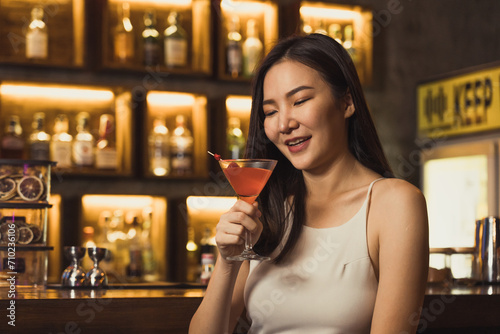 Asian women drinking cocktails and having fun at the bar at night.
