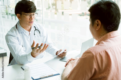 Male patient listening to doctor at desk and consulting with healthcare in hospital.