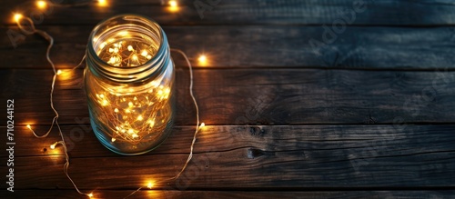 Fairy lights in a glass jar on dark wooden table, shot from above.
