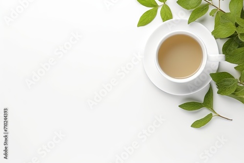 Top view of a cup of tea and tea leaf on a white desk with empty space for text
