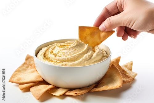 Vertical format photo of pita bread dipped in hummus on white background with empty space for text