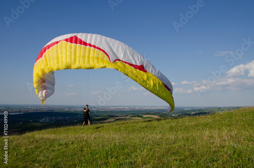 Man standing on field and exercising to maneuver his paraglider