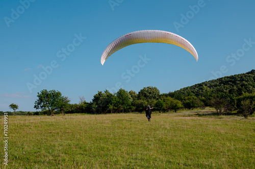 Man running high speed on field in nature ready to takeoff with paraglider 