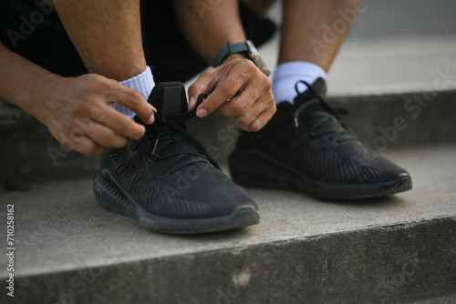 Cropped shot legs of sporty man tying shoelaces before jogging or cardio workout