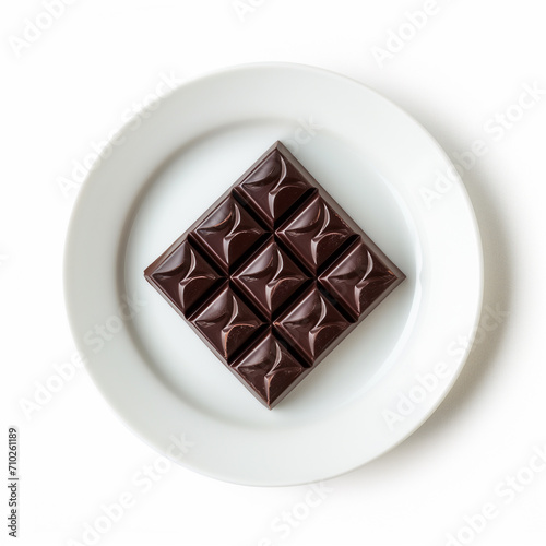 A single square of dark chocolate on a minimalist plate isolated on a white background 