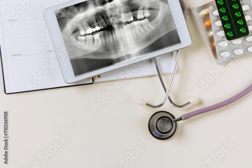 In preparation for treatment, dentist examines an X-ray of patient jaw on digital tablet