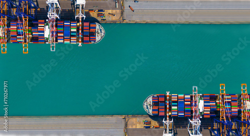 Global transportation and logistic business. Aerial top view over international containers cargo ship at industrial import-export port prepare to load containers with big container loader ship vessel.