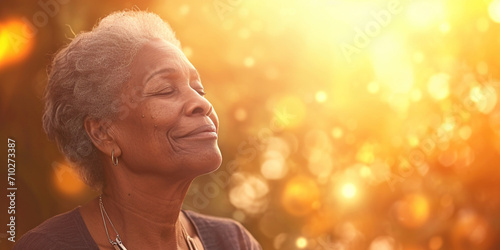 Happy black female smiling in happiness taking deep breath for zen, health or spiritual wellness. Senior African American woman with healing energy light around her feeling good breathing calm peace