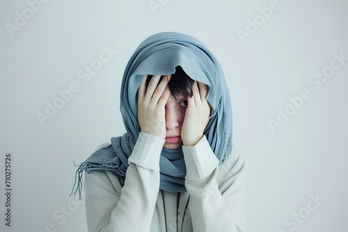 a young woman with a shy, slightly embarrassed look on her face is covering her head with both hands while on front of white background, lively facial expressions. generative AI