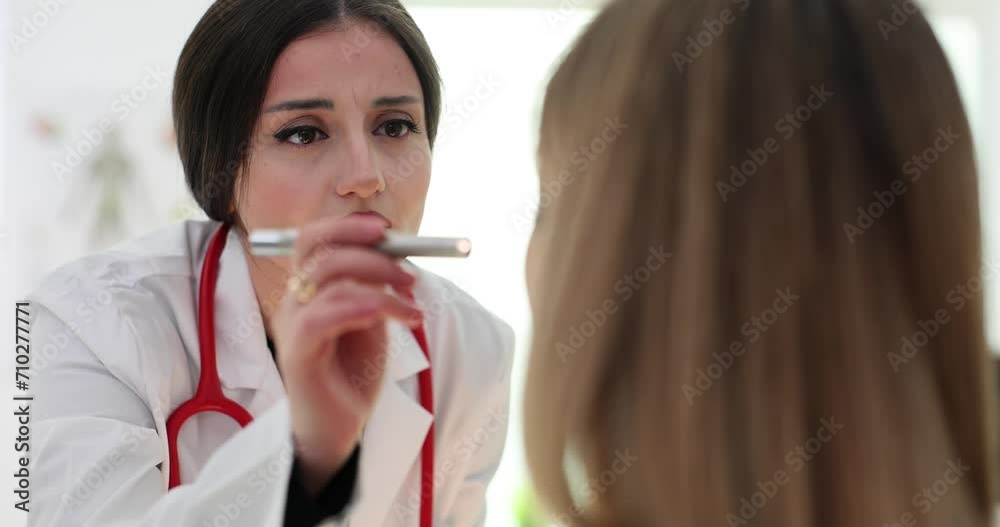 Concentrated pediatrician shines flashlight on patient Concentrated pediatrician shines flashlight on patient