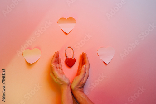 Hands Protecting a Heart Shaped Lock on a Pastel Background. Isolated padlock symbol of marriage and unity in a relationship 
