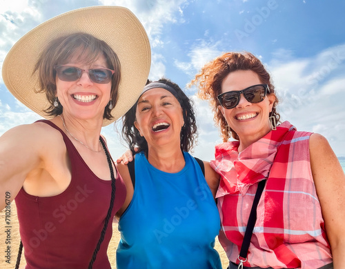 Three laughing women friends  tourists selfie blue sky beach background