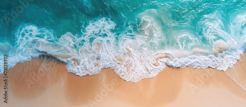 Ocean water viewed from above with clear foam. Sand visible beneath. Beach, summer, vacation, coastline, seashore, travel, tourism, wallpaper.