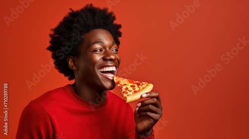 Joyful young man showcasing delicious pizza, vibrant backdrop © iwaart