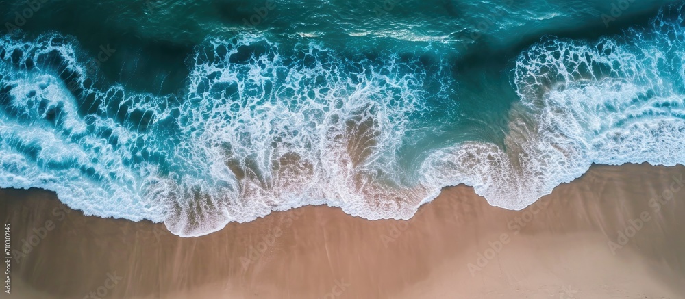 Bird's-eye perspective of ocean waves lapping a secluded sandy coast. Bird's-eye perspective of ocean waves lapping a secluded sandy coast.