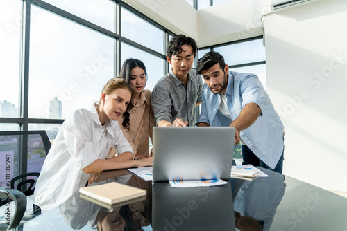 Asian project manager uses laptop displayed data analysis while professional business team brainstorming marketing idea at business meeting. Working together sharing idea  planing strategy. Tracery.