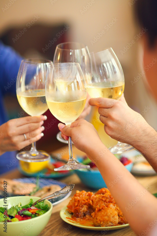 Hands of a group of people cheering with white wine