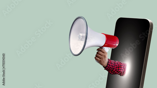 A human hand holding a megaphone comes out from the mobile phone screen
