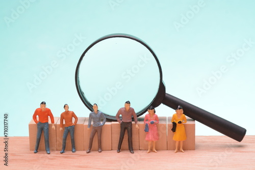 A group of business people huddled together, each holding a magnifying glass, symbolizes their collective focus on examining intricate details, analysis in decision-making.