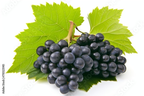 A bunch of grapes, including yellow and black grapes, with leaves on a white surface, suggesting wine.