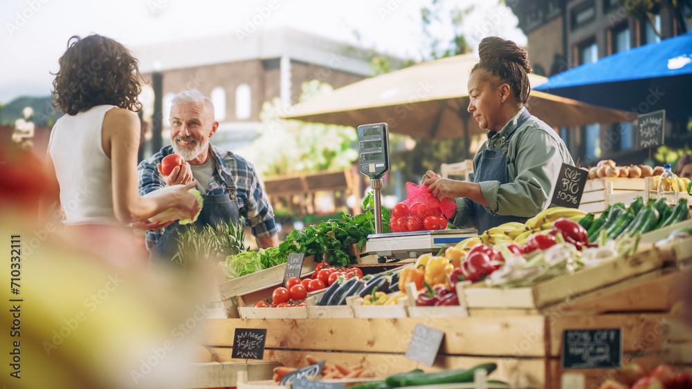 Latin Female Customer Buying Sustainable Organic Tomatoes and Napa Cabbage From a Multiethnic Farmers Couple. Successful Street Vendors Managing a Small Business Farm Stall at an Outdoors Market - obrazy, fototapety, plakaty 