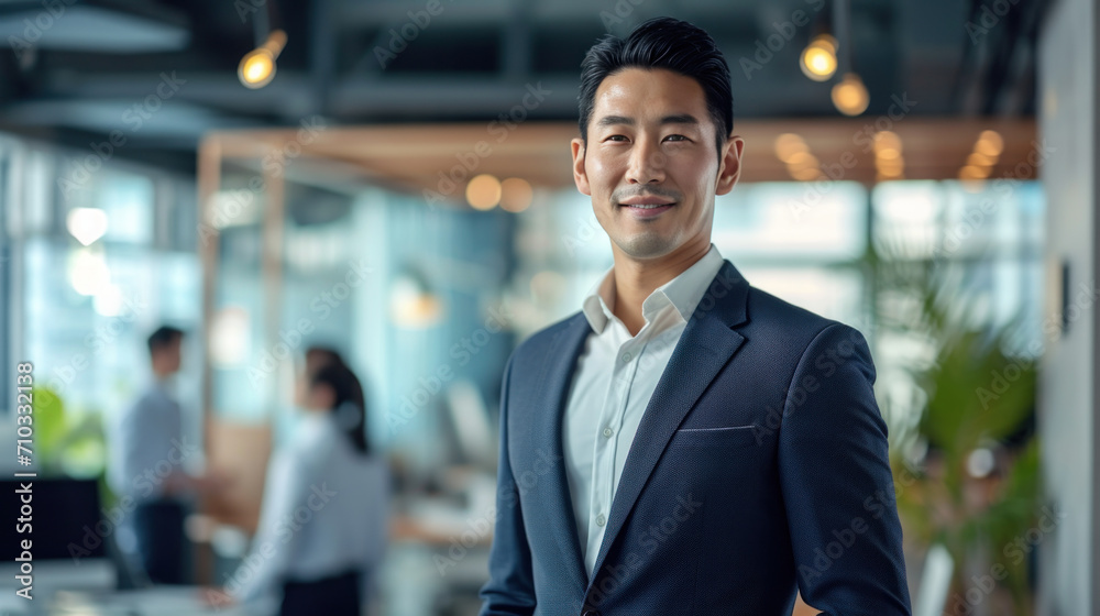 Portrait of a handsome smiling asian businessman boss standing in his modern business company office.