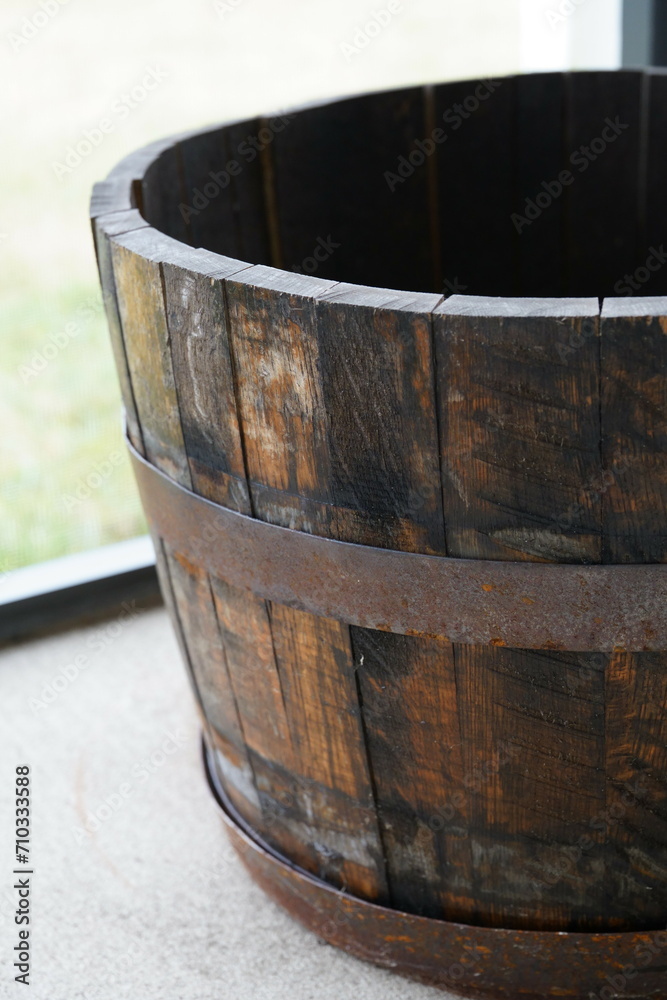 Antique wooden barrel placed on a rustic porch, near a window Antique wooden barrel placed on a rustic porch, near a window