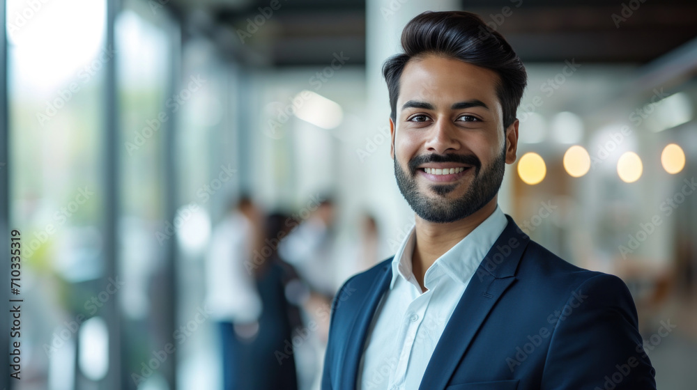 Portrait of a handsome smiling asian indian businessman boss standing in his modern business company office. Portrait of a handsome smiling asian indian businessman boss standing in his modern business company office.