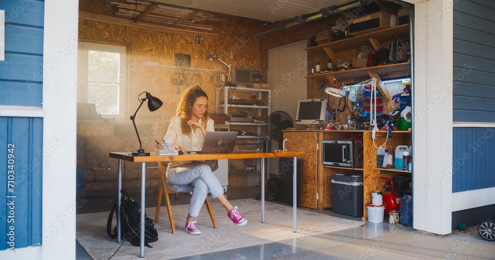 Hispanic Female Programmer Coding On Laptop Computer In Garage At Home. Young Woman Working On Innovative Software As A Service Startup For Business. Digital Entrepreneur Starting Tech Company Concept Hispanic Female Programmer Coding On Laptop Computer In Garage At Home. Young Woman Working On Innovative Software As A Service Startup For Business. Digital Entrepreneur Starting Tech Company Concept