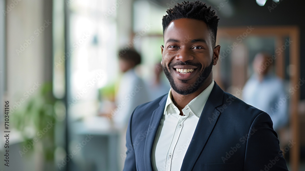 Portrait of a handsome smiling black businessman boss standing in his modern business company office.