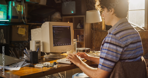 Caucasian Male Computer Engineer Programming On Old Desktop Computer In Retro Garage. Experienced Software Developer Writing Code For New Innovative Portable Device Startup In Nostalgic Nineties.