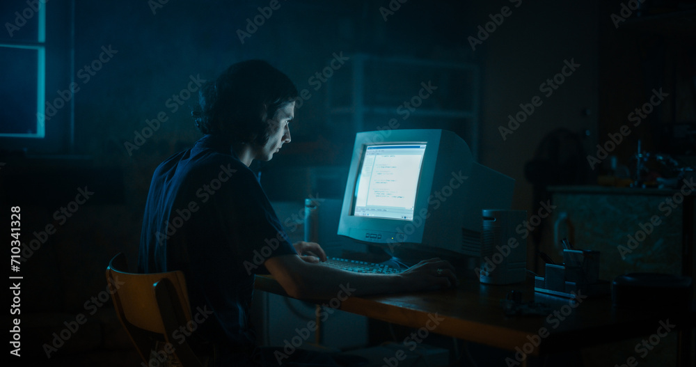 Caucasian Male Web Designer Using Old Desktop Computer In Retro Garage Late At Night. Focused Internet Enthusiast Writing Code At Home. Programming Successful Online Forum Website In Nineties.