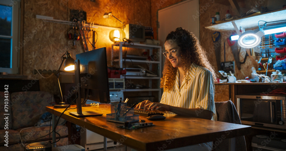 Portrait of Hispanic Female Software Engineer Programming on Desktop Computer In Retro Garage Late At Night. Ambitious Woman Starting Tech Startup Company. Coding Innovative Online Service At Home. Portrait of Hispanic Female Software Engineer Programming on Desktop Computer In Retro Garage Late At Night. Ambitious Woman Starting Tech Startup Company. Coding Innovative Online Service At Home.