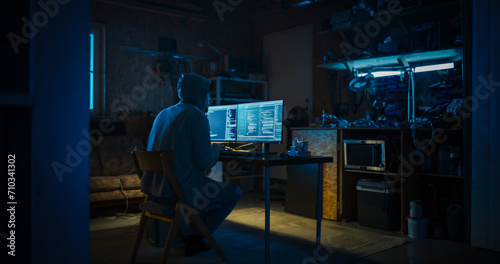 Backview Of Anonymous Professional Programmer Obsessively Writing a Code on His Desktop Computer, Late at Night In Garage. IT Specialist Ethical Hacker Working on Finding Software Vulnerabilities. photo