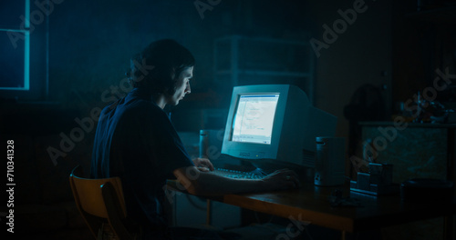 Caucasian Male Web Designer Using Old Desktop Computer In Retro Garage Late At Night. Focused Internet Enthusiast Writing Code At Home. Programming Successful Online Forum Website In Nineties. © Gorodenkoff