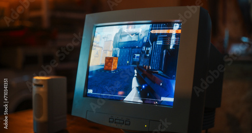 Close Up Of Old Desktop Computer With 3D First-Person Shooter Video Game In Retro Garage Late At Night In Nineties. Dated PC Of Gamer Running Popular Game With Character Playing Against Enemies.