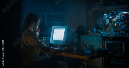 Hispanic Female Programmer Using Old Desktop Computer In Retro Garage Late At Night. Evil Hacker Searching For Software Vulnerabilities, Doing DDOS Attack, Coding Trojan Horse Programs, Stealing Data.