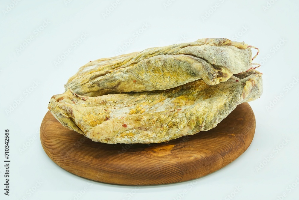 Obraz premium Dried meat without a shell in spices lies on a wooden board. The product is ready to use. White background.