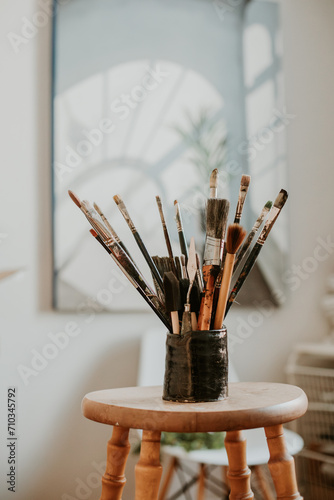 a collection of paintbrushes on a wooden stool in the art studio photo